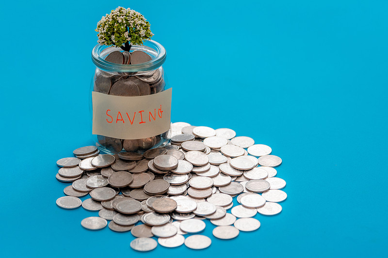 标有“保存”的玻璃罐，上面有正在生长的植物。从玻璃罐里的硬币中生长的植物。投资增长和财务规划背景。图片下载