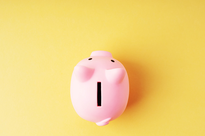 黄色背景上的粉色小猪储蓄罐的高角度视图图片下载