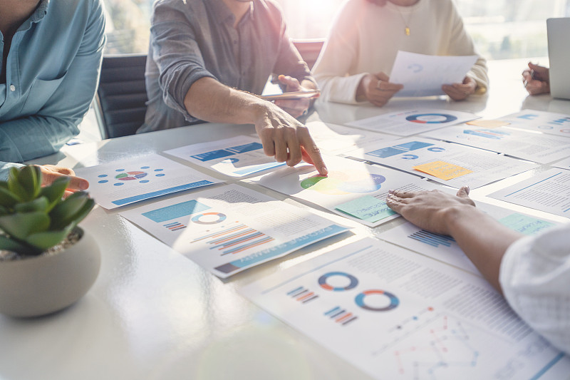 在商业演示或研讨会上，在董事会会议室的桌子上处理文书工作的多种族群体。图片下载