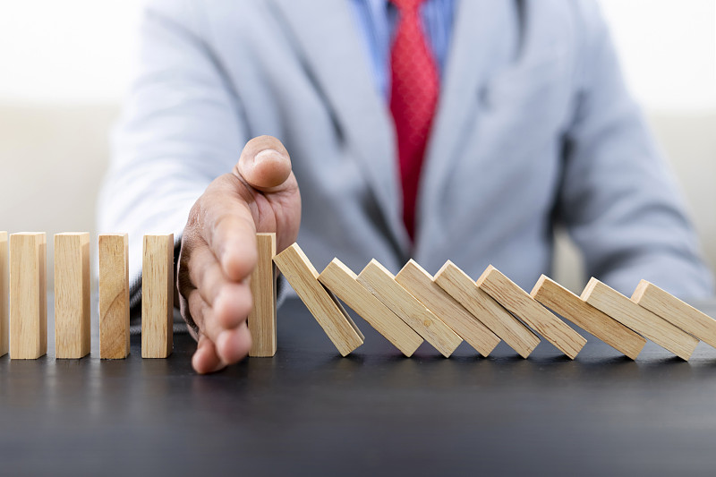 商人把木块放在塔上概念风险控制，规划和战略的业务。替代风险概念，风险使业务增长的概念与木块图片下载