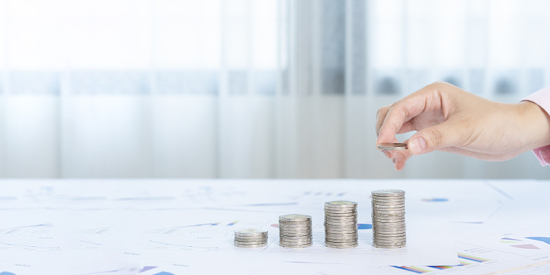 手里拿着一堆钱硬币，以显示业务增长的概念。图片下载