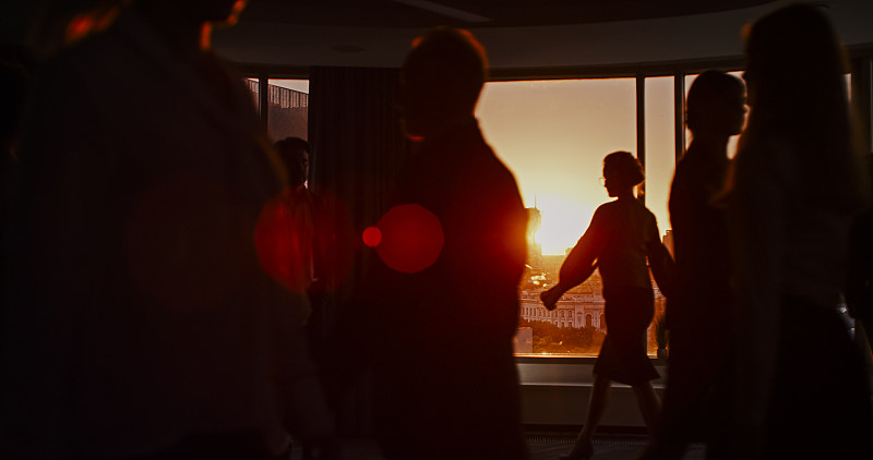 落日余晖映衬着摩天大楼窗户的剪影。股票市场分析会议图片下载