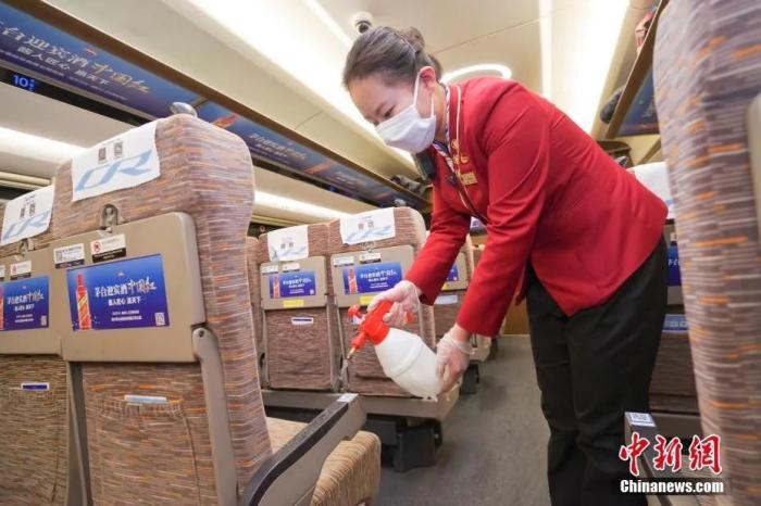 资料图:2月28日晚,在威海开往北京南的G470次列车上,乘务员对座椅扶手消毒。/p中新社记者 贾天勇 摄